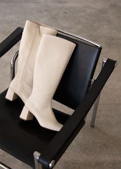 a pair of white boots sitting on top of a black chair next to a metal frame