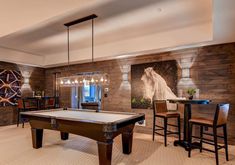 a pool table and chairs in a room with wood paneling on the back wall