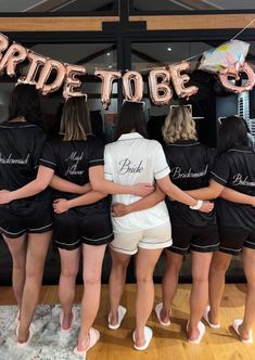 the bride to be sign is hanging in front of her bridal party group, all dressed in black and white