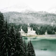 a lake surrounded by snow covered mountains and evergreen trees