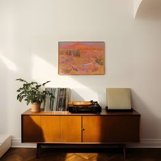 a record player sitting on top of a wooden cabinet next to a potted plant