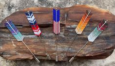 four different colored pins sitting on top of a piece of wood next to a rock