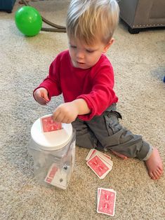 a little boy playing with some cards on the floor