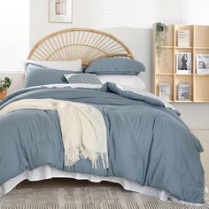 a bed with blue comforters and pillows in a white room next to bookshelves