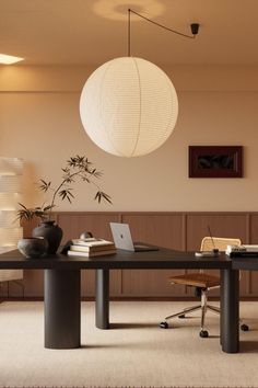 a table with a laptop on top of it in front of a lamp hanging from the ceiling