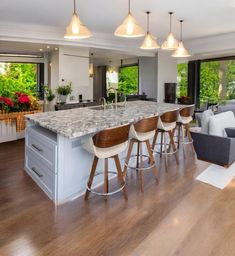 a kitchen island with stools in front of an open living room and dining area