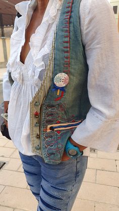 a woman wearing a vest with patches and buttons on it