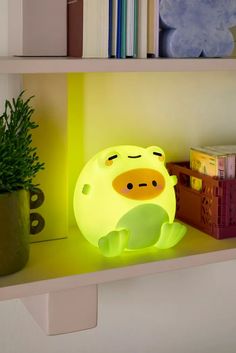 a yellow pig lamp sitting on top of a shelf next to a potted plant