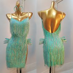 two mannequins dressed in green and gold with beads on the sides, one is wearing a dress