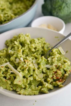 a white bowl filled with guacamole next to broccoli