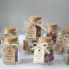 small glass jars filled with different types of dried flowers and labels on the top one says happy valentine's day