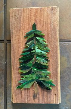 a christmas tree made out of green leaves on a wooden board