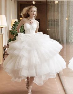 a woman in a white dress walking down a hallway