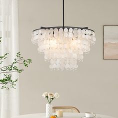 a chandelier hanging over a dining room table with flowers in vases on it