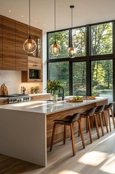 a kitchen with an island and lots of counter space next to large windows that look out onto the woods