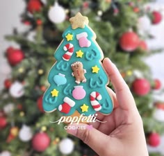 a hand holding up a cookie shaped like a christmas tree