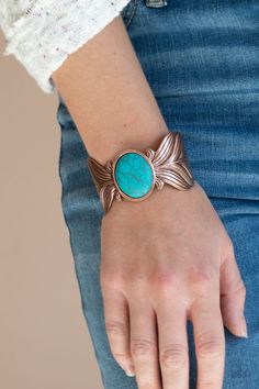 a woman wearing a bracelet with a turquoise stone