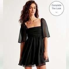 Flattering Short-Sleeve Mini Dress In Our Elevated Organza Fabric And Babydoll Silhouette, Featuring On-Trend Sheer Angel Sleeves, Ruching Details Along The Bodice, Volume Skirt With Pockets And Square Neckline. Imported. Elastic:70% Polyester, 30% Rubber / Body:55% Polyester, 45% Nylon / Lining:98% Polyester, 2% Elastane Turn Garment Inside Out Machine Wash Cold, With Like Colors Only Non-Chlorine Bleach Line Dry Do Not Iron Do Not Dry Clean Evening Mini Dress With Gathered Neckline, Square Neck Mini Dress With Smocked Back For Party, Summer Evening Mini Dress With Gathered Neckline, Flowy Mini Dress With Gathered Sleeves, Flowy Ruched Dress For Night Out, Chic Short Sleeve Mini Dress With Gathered Neckline, Summer Evening Mini Dress With Gathered Sleeves, Chic Short Sleeve Mini Dress With Ruched Bodice, Black Mini Dress With Gathered Sleeves For Spring