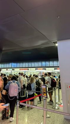 people waiting in line at an airport for their luggage