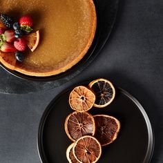 there is a plate with oranges and berries on it next to a pancake