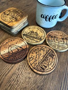 four coasters on a wooden table with a coffee cup and two cups in the background