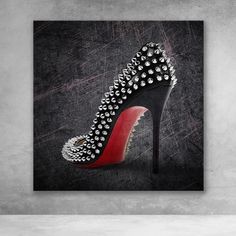 a black and red high heeled shoe with silver spikes on the side, against a gray background