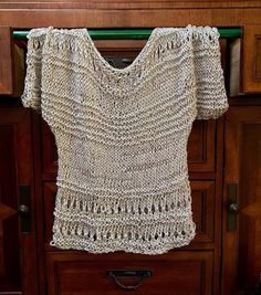 a crocheted top hanging on a wooden cabinet