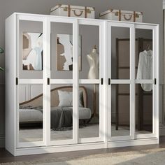 a white closet with mirrored doors and clothes on hangers next to a bed in a room