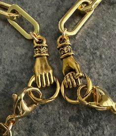 two pairs of gold colored metal chains with hands on them