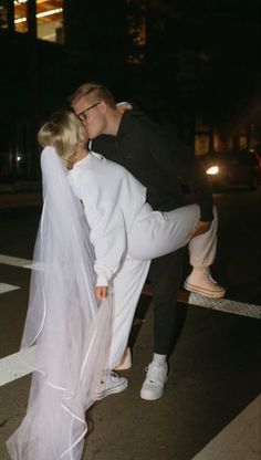 a man and woman kissing in the middle of a crosswalk at night with their arms around each other