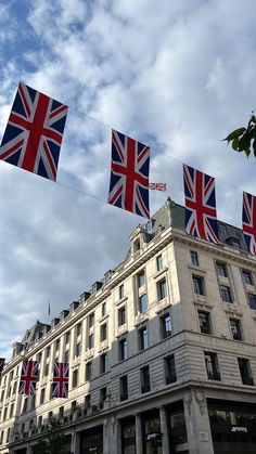 the british flag is flying in front of a large building with flags on it's roof