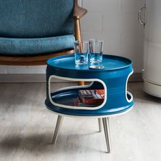 a blue table with two glasses on it and a magazine in the bottom shelf that is open