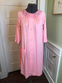 A beautiful piece. This short robe is made of 100% nylon knit fabric in a medium pink.  It features a small scoop neckline with ruffled floral lace yoke, 3/4 raglan sleeves, patch pocket with lace, a-line body and a covered button front closure. This garment is clean, with no stains, snags, or holes. Measurements to guide you: Armpit to armpit: 24" Waist across: 25" Hips across: 29" Sleeve: 16" Length from top of shoulder to hem: 36.5" Please compare your own measurements with those provided above for assurance of fit. Tag says small, but this could easily fit a medium or large as well! Decade: 60s-70s Fabric: Nylon Knit Size: M Condition: Great Brand: Shadowline, Made in USA It's a delight to pick through time for you to find these vintage treasures. Solid Color Spring Nightgown For Daywear, Fitted Spring Sleepwear For Home, Feminine Fitted Long Sleeve Nightgown, Fitted Pink Sleepwear For Home, Long Sleeve Pink Nightgown For Spring, Spring Stretch Nightgown With Lace Trim, Fitted Pink Nightgown For Spring, Pink Stretch Nightgown For Loungewear, Spring Stretch Nightgown