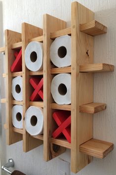 several rolls of toilet paper are placed on wooden shelves with red tape across them,