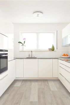 a kitchen with white cabinets and wood flooring in the middle, along with an oven