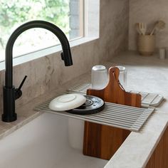 a kitchen sink with a cutting board and utensils on the bottom shelf next to it