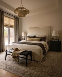 a bedroom with a large bed and two lamps on either side of the bed, in front of a sliding glass door