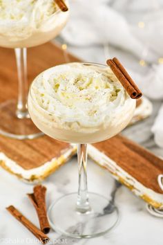 two glasses filled with whipped cream and cinnamon sticks