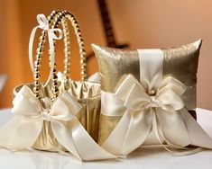 two gold wedding garters with white bows and pearls on the side, sitting next to each other