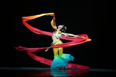 a woman is dancing with red and yellow streamers