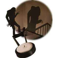 the shadow of a woman standing on top of a table next to a lit candle