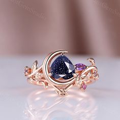 a gold ring with a blue and purple stone in the center on a white surface