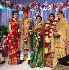 a group of people standing next to each other in front of a flower covered stage