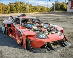 a red sports car parked in a parking lot with its hood up and engine on