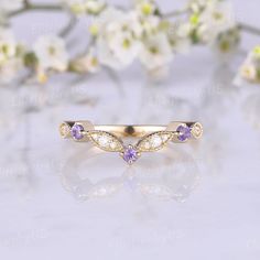 a gold ring with amethorate and diamonds on it sitting next to flowers