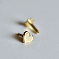 "Sweet little solid gold Heart stud, handcrafted in 14k gold, this pin is available in a variety of closure options for different types of piercings. A cute stud for all ages! * Gold - 14K Solid Gold * 4mm*4mm * Standard length of the post below design is 6-7mm. It can be adjusted as per requirements as well. DIAMOND NOSE PIN : https://www.etsy.com/listing/267480507/ ROUGH EMERALD NOSE STUD : https://www.etsy.com/listing/267480037/ If you like this pin, please press \"Pin it\" button on the righ Dainty 14k Gold Cartilage Earrings For Gift, 14k Yellow Gold Cartilage Earrings For Gift, Dainty 14k Gold Cartilage Earrings As Gift, 14k Yellow Gold Cartilage Earrings, Dainty Tiny Gold Heart Earrings, Gold Heart Cartilage Earrings For Everyday, Gold Heart-shaped Cartilage Earrings, Everyday Gold Heart Cartilage Earrings, Hypoallergenic Yellow Gold Cartilage Earrings As Gift