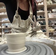 a woman is making a vase out of clay