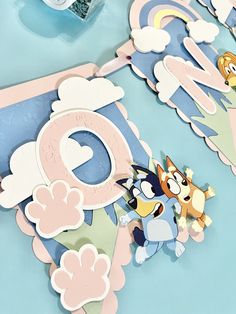 an assortment of paper cut outs on top of a blue table cloth with cartoon characters