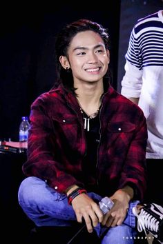 a young man sitting on the ground smiling