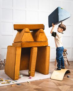 a young boy is playing with a giant piece of furniture that looks like a house